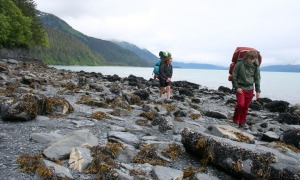Photos by Clark Fair, Redoubt Reporter. Kelty and Olivia Fair pick their way through a field of boulders draped in seaweed and covered in barnacles and blue mussels. This is typical of the walking conditions between Tonsina Point and Derby Cove on a hike to Caines Head outside Seward.